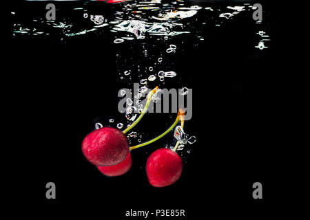 Red Cherry ins Wasser fallen. Stockfoto