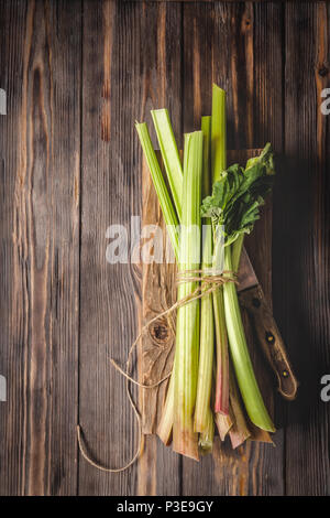 Stämme der frische junge Rhabarber mit Küchenmesser auf Schneidebrett Zutaten für Lebensmittel Rezepte gesunde Ernährung detox Bio Lebensmittel Gemüse auf Holz- Bac Stockfoto