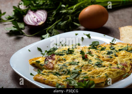 Omelett aus Eiern, Speck, Käse und Zwiebeln auf Platte Stockfoto