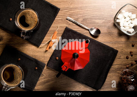 Ansicht von oben auf die Tassen Kaffee auf schwarze Servietten in der Nähe der roten Kaffeemaschine. Stockfoto