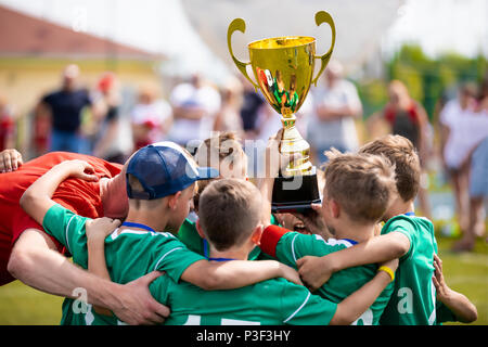 Junge Fußballer Holding Trophäe. Jungen feiert Fußball-Fußball-Meisterschaft. Winning team Sport Turnier für Kinder. Stockfoto