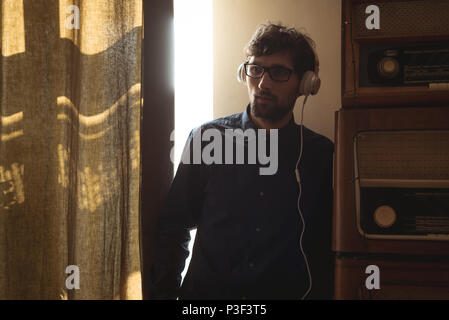 Man Musik hören über Kopfhörer im Wohnzimmer Stockfoto