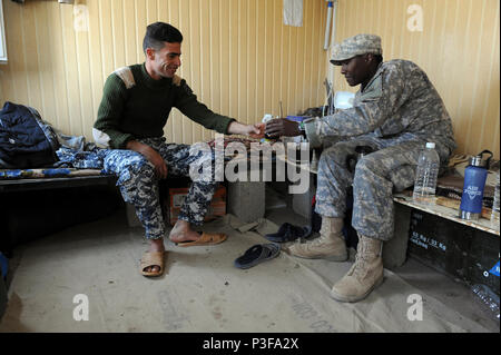 Ein US-Soldat mit Sitz und die Konzernzentrale, Spähtrupp, 1.Bataillon, 30 Infanterie, 2nd Brigade Combat Team, 3rd Infantry Division, Aktien eine Kaffeepause mit einem Mitglied der Irakischen Notdienste bei einer Verkehrskontrolle in Kirkuk, Irak, Feb 2. Soldaten von 1-30 IR-Erhaltung der Sicherheit innerhalb des TCP während Irakische Personal führt die Tag-zu-Tag. Stockfoto