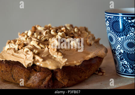 Hausgemachtes walnuss Kaffee und Kuchen mit glace Vereisung, und mit gemusterten Becher Kaffee auf Seite Stockfoto