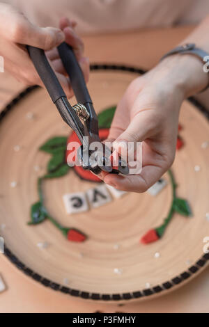 Arbeitsplatz eines Mosaik Master: weibliche Hände, mit einem Mosaik Element auf dem Tisch. Master legt das Mosaik auf einer Platte Masterclass handgefertigte Stockfoto