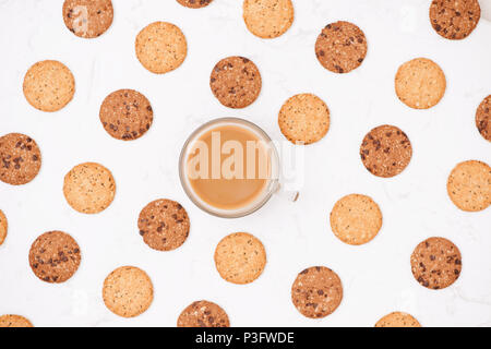 Tasse Kaffee unter Muster von verschiedenen Shortbread und Hafer cookies mit Müsli und Rosinen auf schwarzem Holz- Hintergrund. Ansicht von oben, flach. Stockfoto