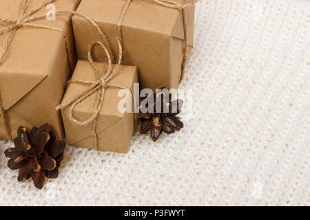 Blick von oben auf die geschenkboxen in schwarz-weiß gestreiften und golden gepunktete Papier mit Pinien und Kegel auf einem weißen Holz Hintergrund gewickelt. Weihnachtsgeschenke p Stockfoto