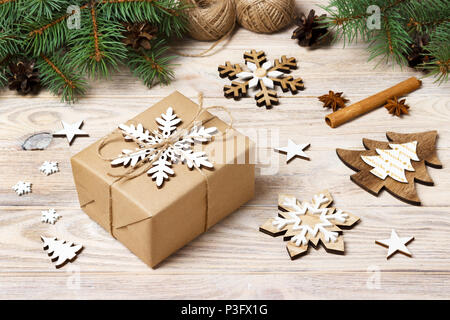 Weihnachten Hintergrund mit geschenkboxen in braunes Packpapier eingewickelt, Tannenbaum Äste, Tannenzapfen, Zimtstangen und Sterne Anis auf weißem Holz- Hintergrund Stockfoto