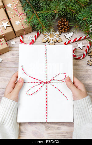 Blick von oben auf die Weihnachten Brief in der Hand. Nahaufnahme der Hand leer Merkzettel auf Holztisch mit Weihnachten Dekoration. Stockfoto