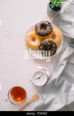 Ansicht von oben von Chocolate Cake Donuts mit gesalzenem Karamell Glasur mit einer Tasse Espresso auf Marmor tisch. Nachmittag mir Zeit Buch lesen mit desse Stockfoto