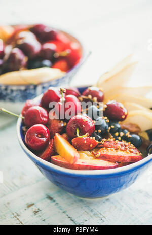 Smoothie Schale mit frischen schwarzen Kirschen, Kokosflocken, Mandeln und Kakao Nibs. Marmor Hintergrund. Ansicht von oben. Platz kopieren Stockfoto