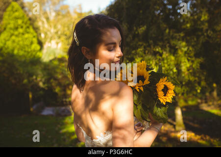 Braut riechen eine Sonnenblume Blumenstrauß im Garten Stockfoto