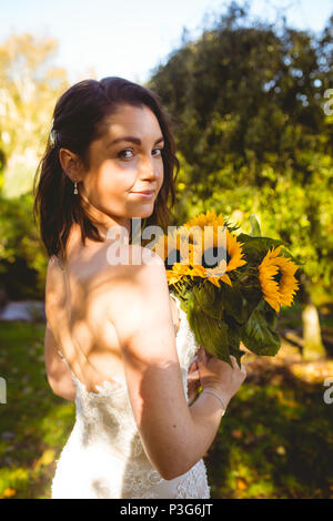 Schöne Braut Holding eine Sonnenblume Blumenstrauß im Garten Stockfoto