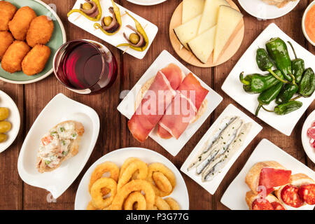 Das Essen von Spanien. Ein Foto von verschiedenen spanischen Tapas, geschossen von oben auf einen dunklen rustikalen Textur. Schinken, Käse, Wein, Oliven, Kroketten, Cala Stockfoto
