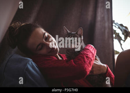 Lächelnde Frau ihr Haustier Katze zu Hause umarmen Stockfoto