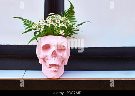 Blumentopf in der Form eines Schädels auf einem Regal im Freien an einem Street Cafe Stockfoto