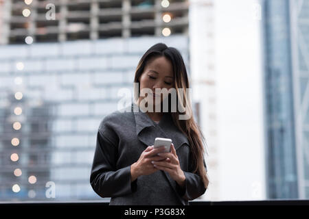 Geschäftsfrau, die mit ihrem Mobiltelefon Stockfoto