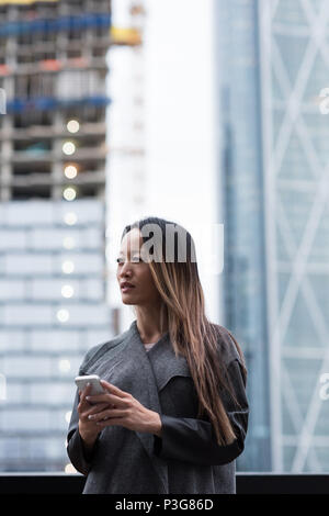 Geschäftsfrau weg schauen, während Sie Ihr Mobiltelefon Stockfoto