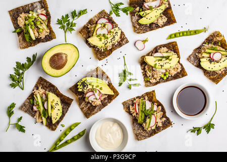 Brauner Reis, Avocado, Erbsen nori Wraps mit Sojasauce und tahini Dressing auf weißem Marmor Hintergrund, Ansicht von oben Stockfoto