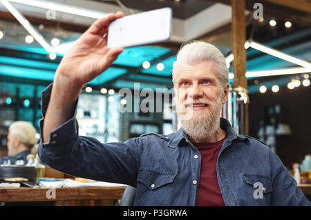 Aufmerksame reifer Mann am Telefon suchen Stockfoto