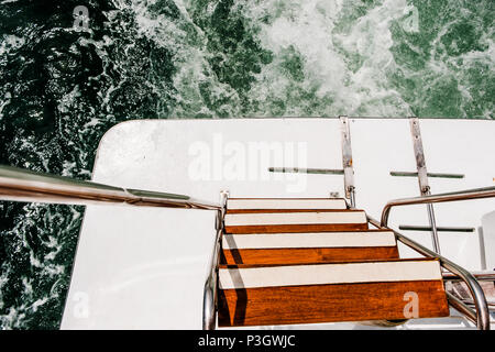 Welle am Meer Wasser Oberfläche hinter sich schnell bewegende Power Boat verfolgen. Hintere schwimmen Plattform der Boot mit Holztreppe und Metall Handläufe. Ansicht von oben. Stockfoto