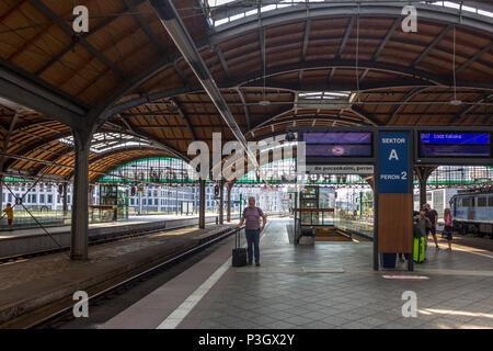 Ältere Mann wartet allein mit kleinen Koffer auf Plattform für Zug bei Wrocław Główny - Breslauer Hauptbahnhof Stockfoto