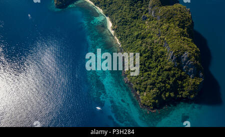 Antenne drone Blick auf die Boote im klaren Meer, über ein tropisches Korallenriff, umgeben von aufragenden Dschungel bedeckten Berge Stockfoto