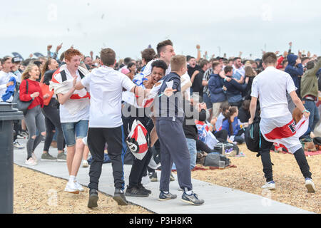 Brighton, UK. 18 Juni, 2018. England Fußball Fans auf das Spiel auf einem riesigen Bildschirm auf Brighton Seafront feiern, als Harry Kane gibt Ihnen eine frühe Leitung: Simon Dack/Alamy leben Nachrichten Stockfoto