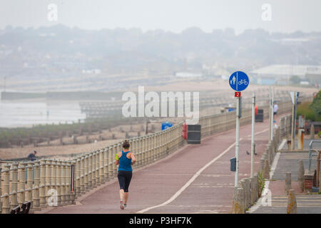 Hastings, East Sussex, UK. 19 Jun, 2018. UK Wetter: miserablen Start in den Tag mit einem Trübe Aussichten für den Rest des Tages mit Temperaturen bis 19°C. Eine Frau geht für ein Run auf die Küste mit der Stadt Bexhill in der Ferne. © Paul Lawrenson 2018, Foto: Paul Lawrenson/Alamy leben Nachrichten Stockfoto