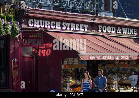 Essen Wein und Obst für den Verkauf auf Stoke Newington Church Street an einem hellen, sonnigen Tag in London unter einem roten Markise Stockfoto