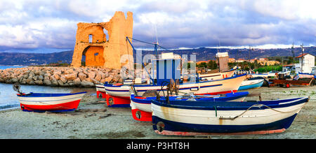 Alte Turm über Sonnenuntergang in Briatico, mit Blick auf die traditionellen Fischerboote, Kalabrien, Italien. Stockfoto