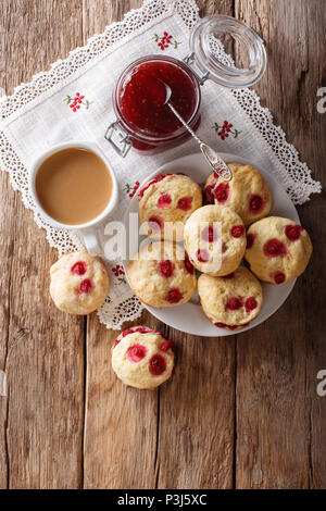 Englisch brötchen Wandleuchten mit roten Johannisbeeren sind mit englischen Tee und Marmelade in der Nähe serviert - auf den Tisch. Vertikal oben Ansicht von oben Stockfoto