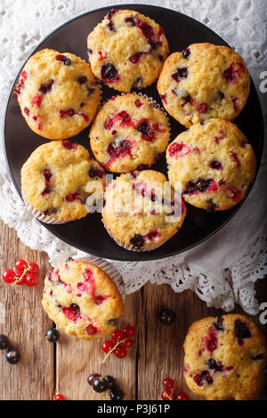 Frisch gebackene Muffins mit schwarzen und roten Johannisbeeren Beeren close-up auf den Tisch. Vertikal oben Ansicht von oben Stockfoto