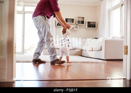 Vater, Tochter lernen zu Hause zu gehen, Seitenansicht Stockfoto