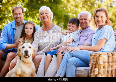 Drei generation Familie sitzt mit Hund im Garten Stockfoto