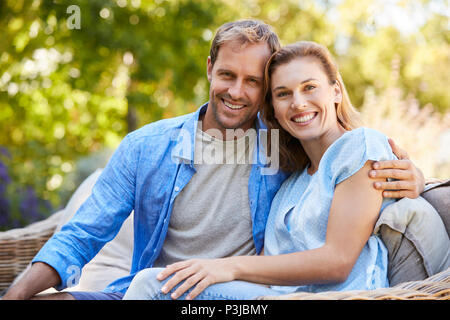 Glückliche junge weiß Paar sitzen und in den Garten Stockfoto