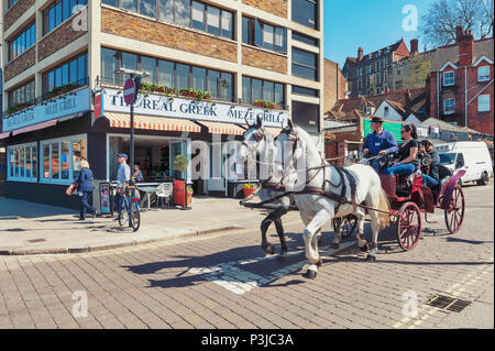 Touristen genießen eine Sightseeing Tour durch einen Vintage hackney Beförderung auf der weißen Pferde in der Stadt Windsor, Berkshire, England, UK gezeichnet Stockfoto