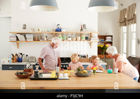 Großeltern und ihre Enkelkinder im Gespräch in der Küche Stockfoto