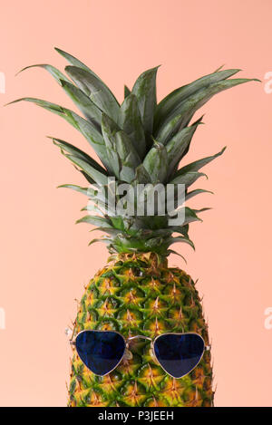 Nahaufnahme einer Ananas tragen ein Paar der herzförmigen Sonnenbrille auf eine blass rosa Hintergrund Stockfoto