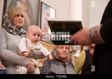 Belarus, Gomel, 24. Februar 2018. Kirche der Birken. Kind in die Arme der Mutter. Taufe des Babys. Akzeptieren Sie den Glauben. In der Kirche des Neugeborenen. Stockfoto