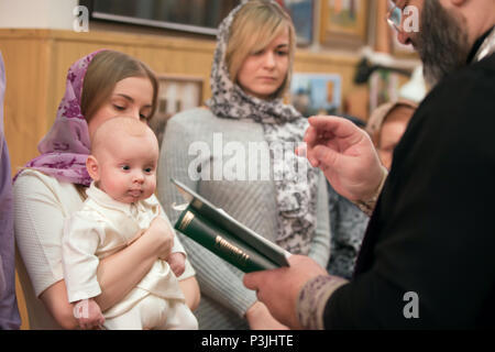 Belarus, Gomel, 24. Februar 2018. Kirche der Birken. Taufe des Babys. Die Mutter hält ein Kind in die Arme der Ritus der Taufe Stockfoto