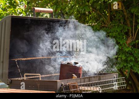 Holzkohle rauchen beginnt in einem Kamin Starter für ein Barbecue. Stockfoto