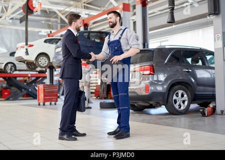 Arbeitnehmer Händeschütteln mit Client in Auto Service Shop Stockfoto