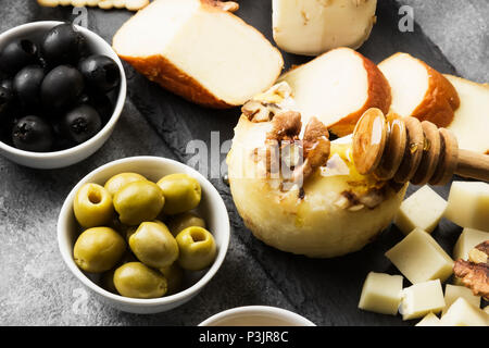 Snacks mit Wein - verschiedene Arten von Käse, Feigen, Nüsse auf grauem Hintergrund Stockfoto