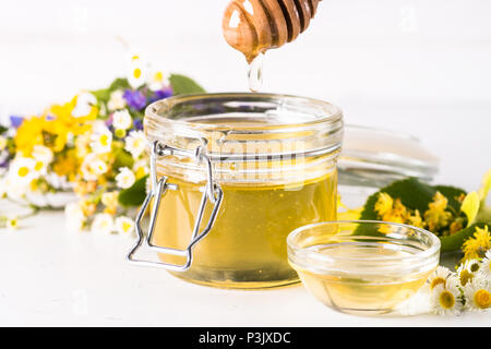 Honig in einem Glas mit wilden Kräutern auf Weiß Stockfoto