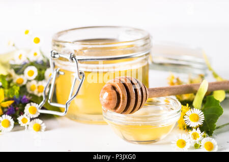 Honig in einem Glas mit wilden Kräutern auf Weiß Stockfoto