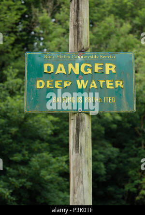 Gefahr Tiefwasserschild mit grünem Hintergrund, gelber Schriftzug abblätternder, montiert auf Holzmast im Burrs Country Park Bury lancashire uk Stockfoto