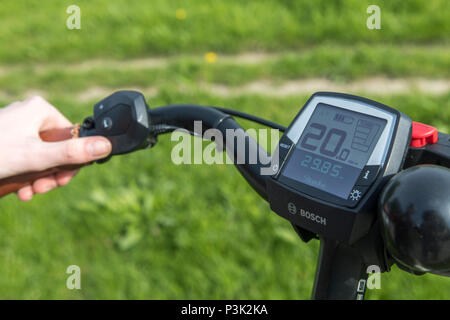 Junge Frau fährt ein e-Bike, Elektro Bike, Elektromotor unterstützt fahren, Fahrrad Lenker mit Tachometer eine Batterie anzuzeigen, Stockfoto