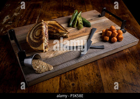 In-House geheilt geräuchert Pastrami, House-Made Sauerkraut auf gegrilltem Marmor Roggen, Schweizer Käse, I.P.A. Scharfer Senf, Murph Soße auf Schneidebrett Stockfoto