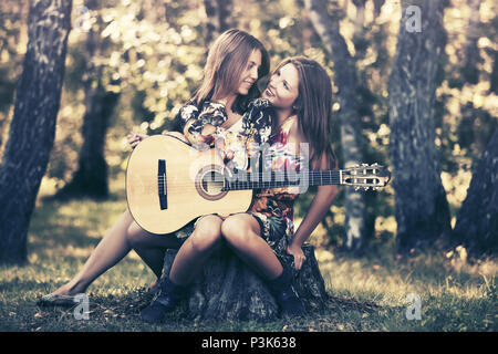 Zwei junge Mädchen mit Gitarre im Sommer Wald Stockfoto